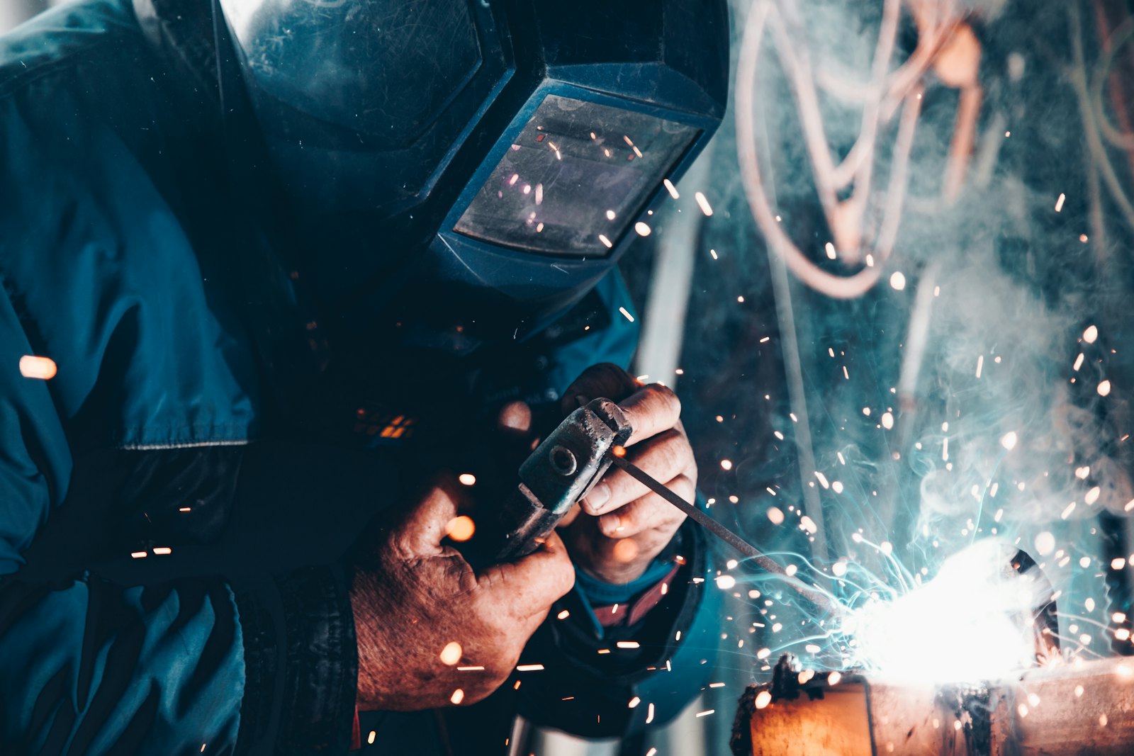 Welder in protective gear working on a steel frame