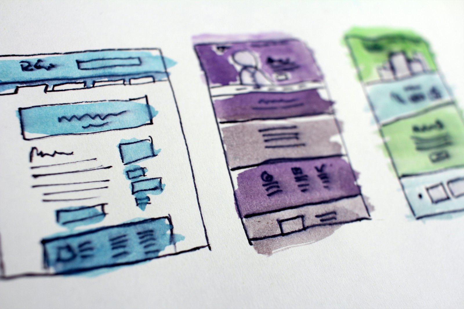 Website wireframes sketched on paper beside a laptop